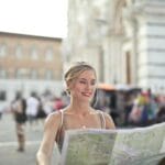 Uśmiechnięta turystka z mapą zwiedzająca Bonn w słoneczny dzień