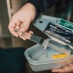 Dłoń trzymająca strzykawkę z samochodowej apteczki pierwszej pomocy