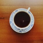 Filiżanka kawy na ozdobnym spodku na drewnianym stole