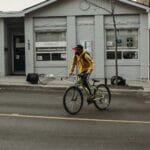 Rowerzysta w żółtej kurtce jedzie ulicą obok budynku w Bielefeld