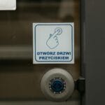 Zbliżenie na drzwi z polskim napisem przycisku otwierania