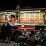 Nocny food truck z burgerami i ludźmi jedzącymi na zewnątrz