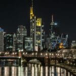 Nocna panorama Frankfurtu z oświetlonymi wieżowcami i odbiciem w Menie