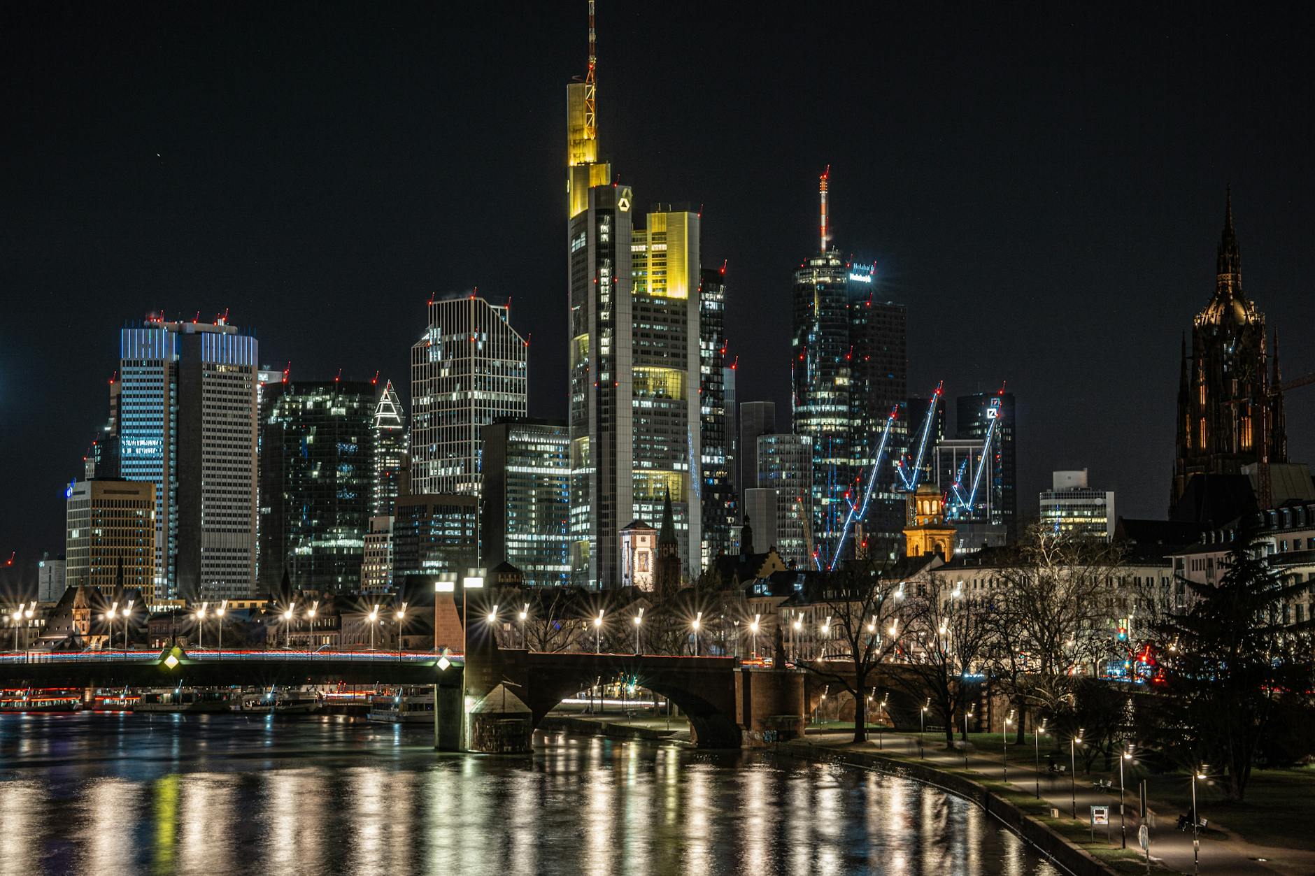 Nocna panorama Frankfurtu z oświetlonymi wieżowcami i odbiciem w Menie