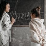 Nauczyciel pokazuje uczniowi zapis nutowy w klasie